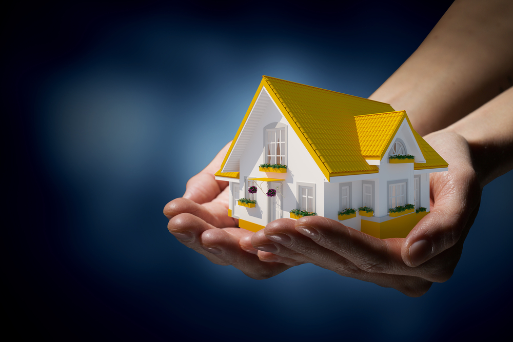 Human hands holding model of dream house