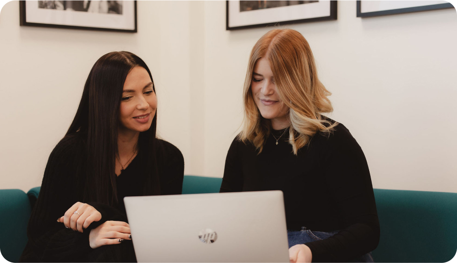 Two Onecom employees looking at laptop on sofa